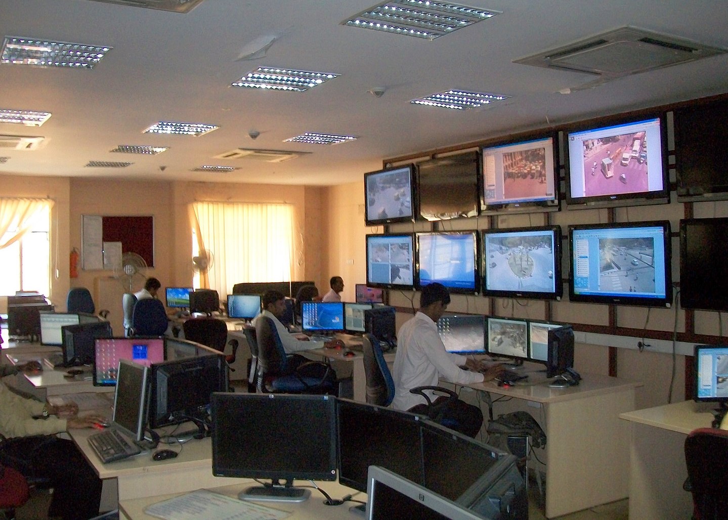 An inside view of a traffic management center with computer monitors displaying video camera feeds of traffic